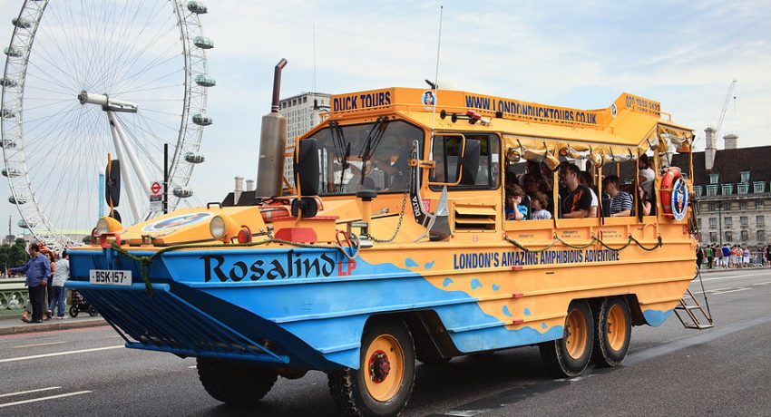 London, UK - August 19, 2012:  A London Duck Tour amphibious DUCW vehicle full of tourists, passing the London Eye on its way to the River Thames